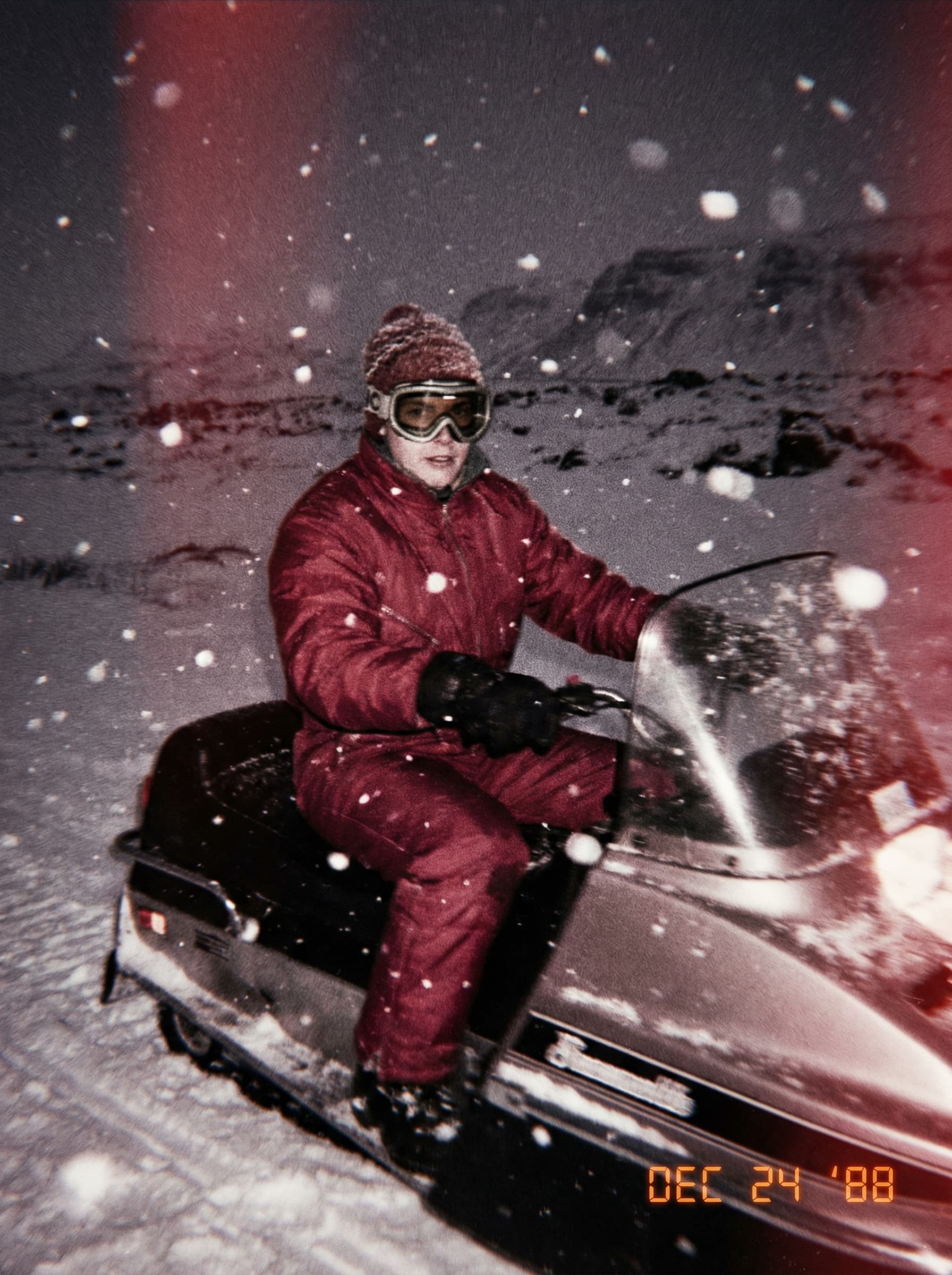 Icelandic landscape, 1980’s, retro fashion model, outdoor clothing, snow goggles, snow, retro, bright colours, nostalgic, analogue photography, moody, abstract, motion blur, film photo taken with a disposable camera, riding snowmobile, nighttime, Realistic,Award winner photography,realistic,Hasselblad H6D camera,80mm lens,F22,1/1000 second,ISO 100,shot on 35mm film --ar 16:9 --v 5.2